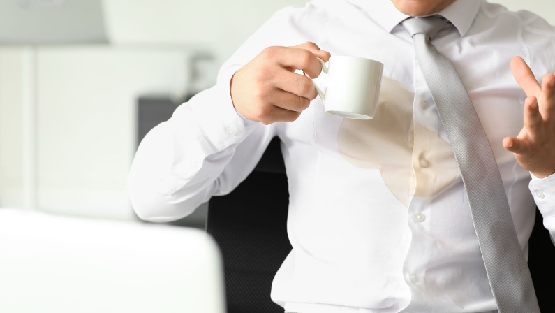 Stressed young businessman with coffee stains on his shirt in office