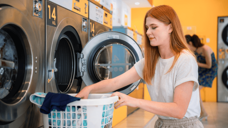 Beautiful young lady doing her weekly washing in a self-service public laundry.
