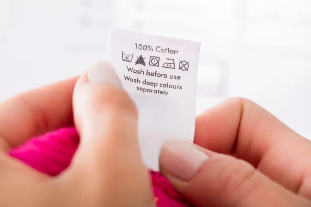Close-up Of Person Reading The Clothing Label Showing Washing Instructions